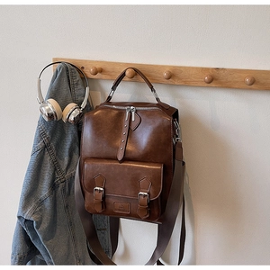 Detail view of vintage dark brown PU leather backpack with magnetic front pocket and silver hardware