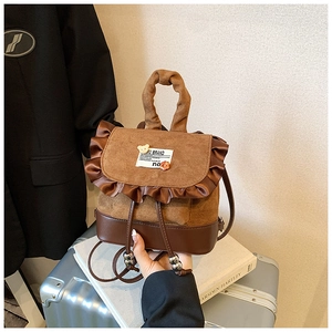 Detailed view of mini brown suede backpack with ruffle trim and cute decorative badges