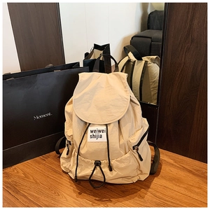 Close-up of beige nylon backpack featuring drawstring closure and small woven label detail