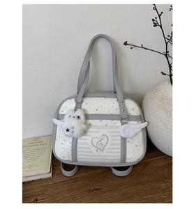 Detail of white and gray square bag with star patterns, wing decor and a plush bear