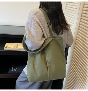 Detail view of large green corduroy tote bag featuring ribbed texture and side brand tag
