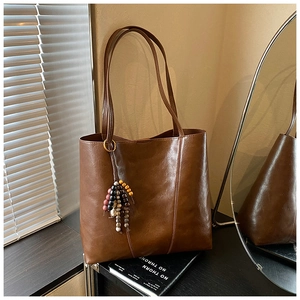 Detail of vintage brown tote bag with glossy leather texture and colorful bead tassel