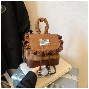 Close-up of brown suede mini backpack with ruffled trim and bear patch detail