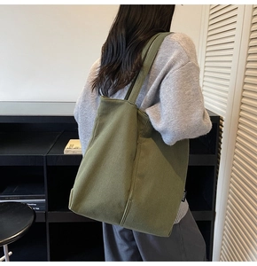 Detail of green corduroy tote bag showing soft ribbed texture and side brand tag