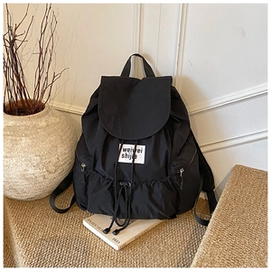 Detailed view of black nylon backpack with drawstring closure and front brand label