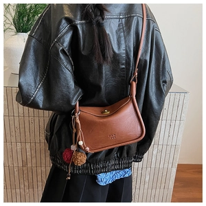 Brown vintage leather crossbody bag with metallic rotary clasp and decorative charms