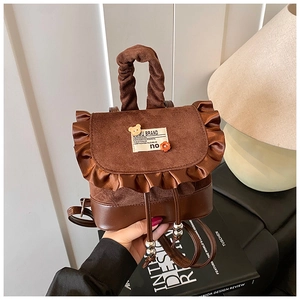 Detail of vintage brown mini backpack with ruffle edge and decorative brand patches
