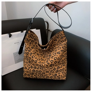 Close-up of leopard print tote bag with black leather straps on a dark sofa