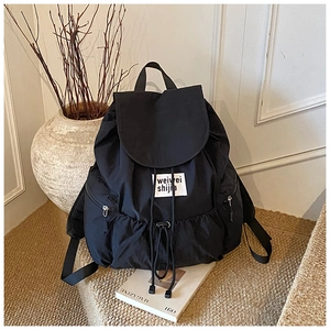 Close-up of lightweight black nylon backpack with drawstring closure and brand label