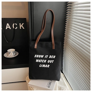Détail du cabas en toile avec typographie blanche et anses en cuir marron de qualité