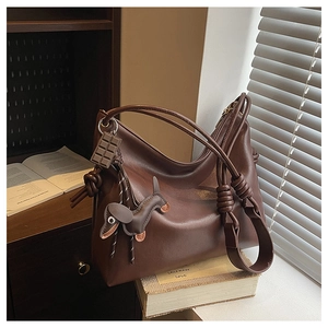 Macro view of dark coffee leather tote featuring a unique knotted strap and dog charm