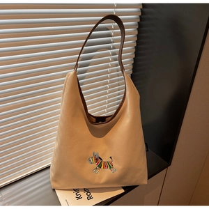 Close-up of canvas tote bag featuring colorful donkey embroidery and brown leather strap