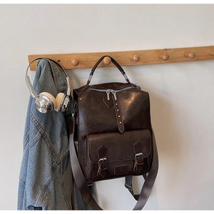 Detailed view of deep brown vintage backpack hanging with denim jacket and headphones