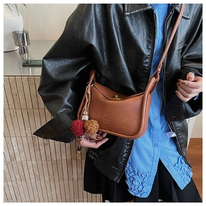 Detail of vintage brown leather crossbody bag featuring a plush charm and PANTOR embossing