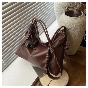 Detailed view of dark brown leather hobo bag with a cute dog and chocolate charm hanging