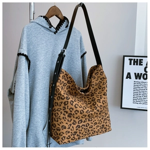 Detail of adjustable black leather strap with metal eyelets on a leopard print hobo bag