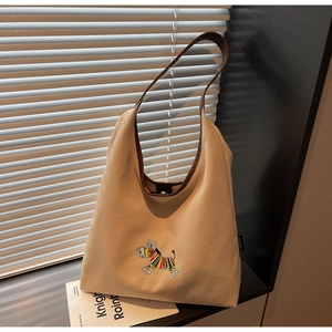 Detail of canvas tote bag featuring colorful zebra embroidery and brown leather strap