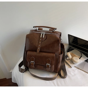Detail of dark brown vintage backpack with textured leather and silver buckles on a desk