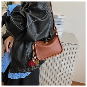Brown vintage pillow bag with metal twist lock and decorative plush charms