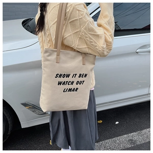 Détail du sac cabas en toile beige avec imprimé lettres noires dans un cadre extérieur