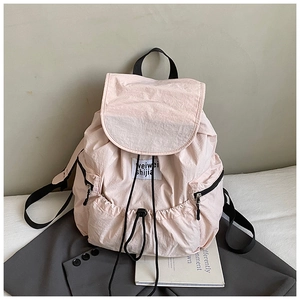 Detail of pink nylon backpack featuring drawstring closure and functional side zipper pockets