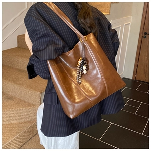 Close-up of brown vintage leather tote bag featuring a colorful beaded tassel charm