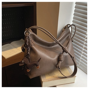 Detail of vintage brown leather hobo bag with unique knot straps and dog-shaped charm