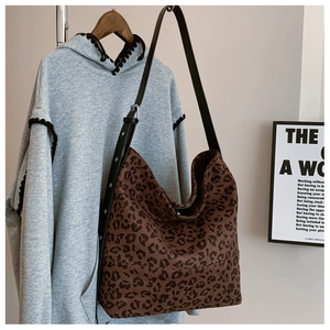 Detail view of large leopard print tote bag with adjustable strap on a hanger