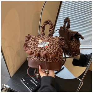 Detailed view of leopard print mini backpack with brown leather base and ruffle trim