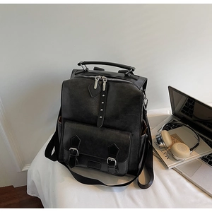 Detail view of a vintage black PU leather backpack with silver buckles and side pockets