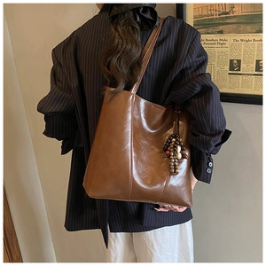 Detail of dark brown tote bag with vintage bead pendant and vertical stitching