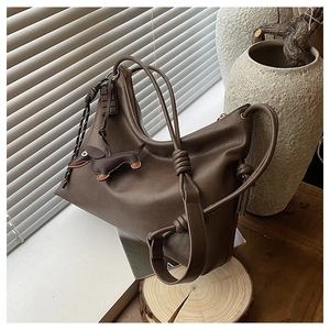 Detail of dark brown hobo bag with a knotted strap and a cute dachshund leather charm