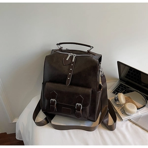 Detail view of dark brown vintage backpack with art book and laptop on a desk