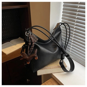 Close-up of black PU leather hobo bag with knotted strap and dachshund charm detail