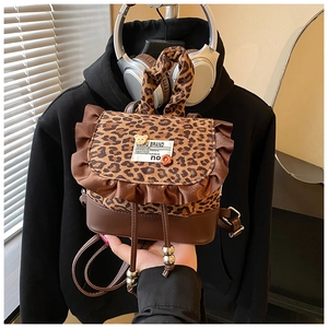 Close-up of leopard print backpack featuring brown ruffled trim and drawstring closure