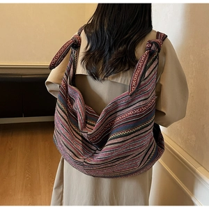 Detail of bohemian ethnic striped woven crossbody bag with stylish shoulder knot design