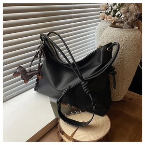Detail of a black hobo bag with a cute dachshund charm in a warm lifestyle setting
