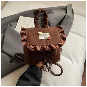 Detail of vintage brown mini backpack featuring ruffle trim and cute bear accessories