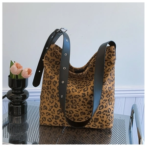 Close-up of leopard print tote bag with black leather wide strap and metal eyelets