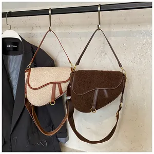 Detail of faux shearling saddle bags in cream and brown with adjustable leather straps