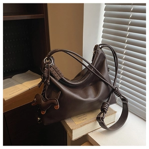 Macro shot of dark brown soft leather tote with knot straps and cute bag charms