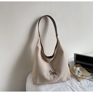 Detail of embroidered rainbow zebra on beige canvas tote bag with brown leather trim
