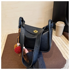 Close-up of black leather pillow bag with gold clasp and decorative fur pompom