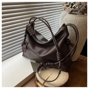 Detail of dark brown vintage hobo bag with knotted straps and decorative pendants