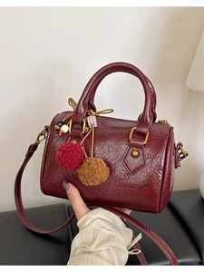 Retro burgundy boston bag with polished leather texture and plush ball charms