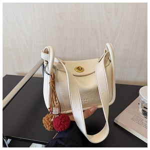 Detail of cream leather pillow bag featuring vintage gold clasp and plush charms