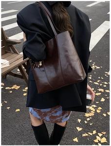 Detail of dark brown tote bag with vintage beads and glossy leather texture outdoors