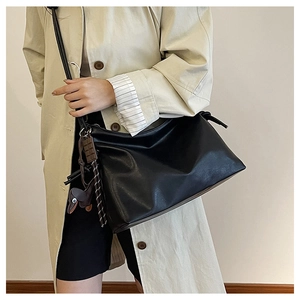 Detail of minimalist black leather bucket bag with dog and chocolate charms