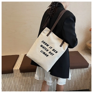 Détail du sac cabas en toile avec anses en cuir marron et texte noir imprimé