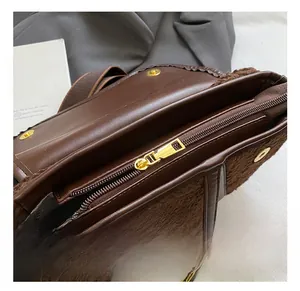 Detail of brown leather saddle bag featuring plush trim and golden metal zipper hardware
